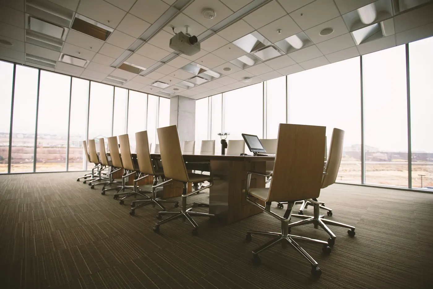 An empty boardroom with a long table and city views